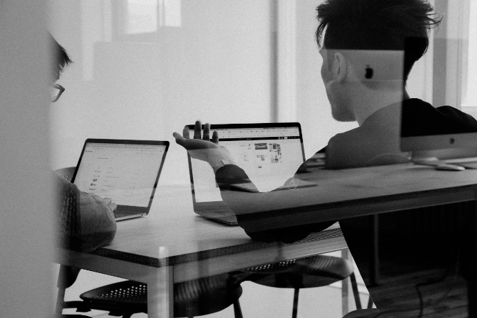 Due colleghi ripresi di spalle che collaborano sul lavoro